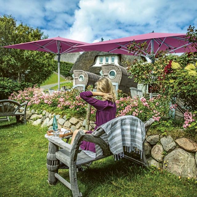 Frau sitzt im Garten und 2 Sonnenschirme sind geöffnet