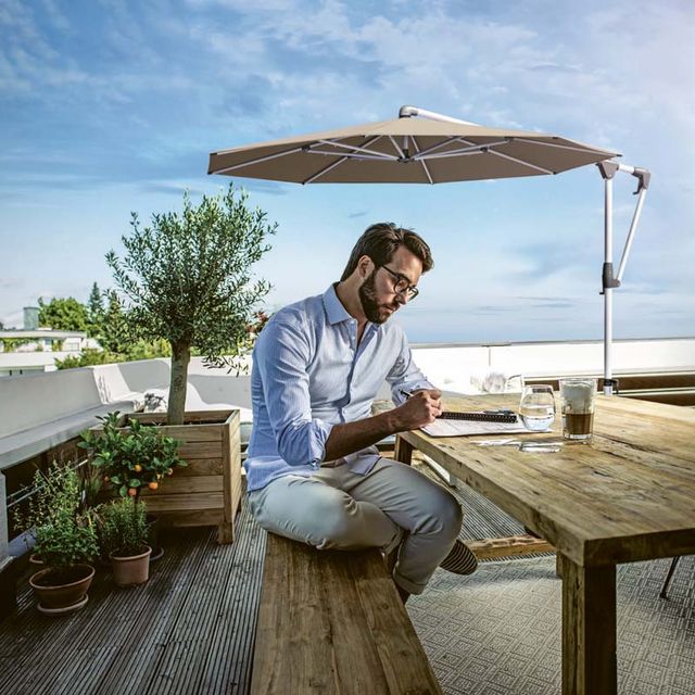 Man sitzt auf Terrasse unter Sonnenschirm